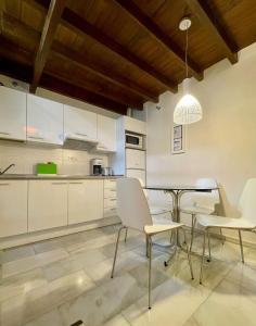 eine Küche mit weißen Schränken sowie einem Tisch und Stühlen in der Unterkunft Embrujo in Granada