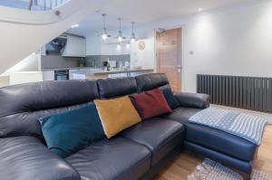 a living room with a black leather couch with colorful pillows at Flat 2 - 2 Bedroom Apartment - Tenby in Tenby