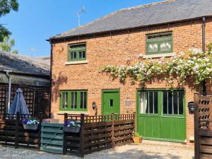 a brick building with green doors and a fence at Piper Cottage, Bilbrough, York in Bilbrough
