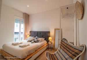 a bedroom with a bed with a chair and a window at Nesha Ericeira Flats in Ericeira