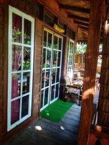 a porch of a cabin with a green floor and windows at ETALAUSER Jungle Gate EcoResort Bukit Lawang in Bukit Lawang