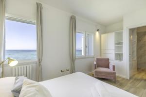 a bedroom with a bed and a chair and the ocean at Villa Blanca del mar in Quartu SantʼElena