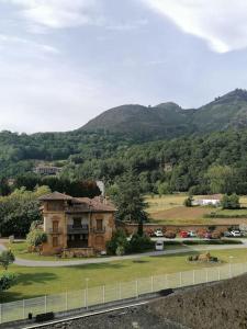 an old building in a field with mountains in the background at Ático 3 hab en centro de Cangas in Cangas de Onís
