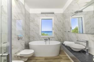 a white bathroom with a tub and two sinks at Villa Blanca del mar in Quartu SantʼElena