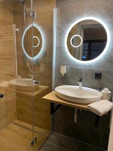 a bathroom with a sink and a shower with a mirror at Hotel Gasthof Käßer in Ansbach