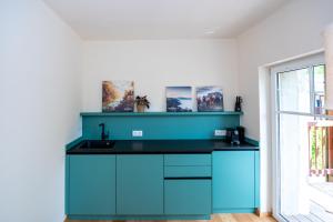 a kitchen with blue cabinets and a sink at NaturparkResort GeoApartment in Gams bei Hieflau