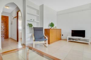 uma sala de estar com uma cadeira e uma televisão em Imperial Puerto 2 3F By IVI Real Estate em Torremolinos