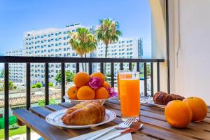 una mesa con naranjas y cruasanes y un vaso de zumo de naranja en Imperial Puerto 2 3F By IVI Real Estate, en Torremolinos