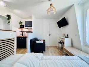 a bedroom with a bed and a desk and a kitchen at La vie en bleu - Studio proche de Paris in Charenton-le-Pont