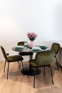 uma mesa com quatro cadeiras e um vaso com flores em Pinea Apartament 304 Apartament przy plaży em Pobierowo