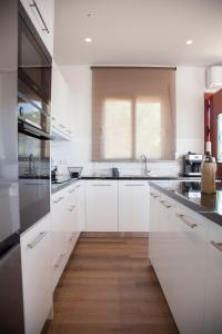 cocina con armarios blancos y suelo de madera en Villa Anthodesmi en Dilináta