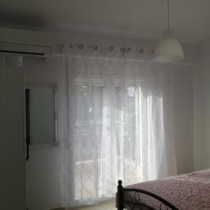 a bedroom with a window with white curtains and a bed at Maisonette Fanari in Fanari