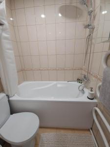 a bathroom with a white tub and a toilet at Haustory Apartment in Klaipėda