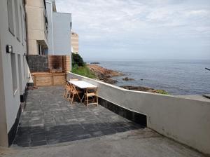 Vila Mariña. Casa marinera con terraza sobre el mar en Caión في Cayón: طاولة وكراسي على شرفة مطلة على المحيط