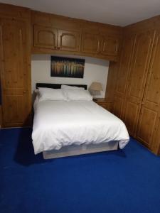 a bedroom with a large white bed with wooden cabinets at Sandra in Streatham Vale