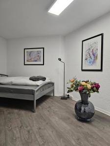 ELW sonnig,Terasse, bis zu 13 Schlafpl. في Obergröningen: غرفة نوم مع سرير و مزهرية مع الزهور