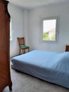 1 dormitorio con cama, ventana y silla en Maison de vacances Bréhal, en Bréhal