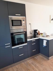 a kitchen with blue cabinets and a microwave at Maison de vacances Bréhal in Bréhal