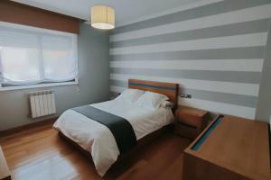 1 dormitorio con 1 cama con pared a rayas en Gran casa pareada con piscina en Vigo. Playa: 9min, en Vigo
