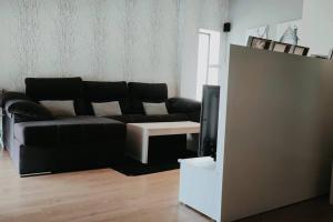 sala de estar con sofá negro y TV en Gran casa pareada con piscina en Vigo. Playa: 9min en Vigo