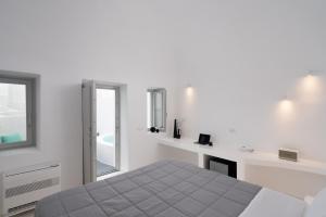 ein weißes Schlafzimmer mit einem Bett und einem Spiegel in der Unterkunft White Concept Caves in Fira