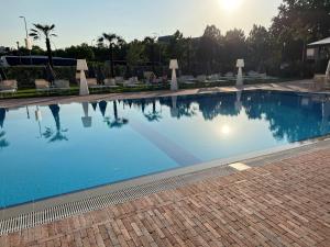 a large blue swimming pool with chairs and trees at The Sydney Hotel in Bologna