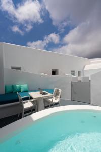 einen Balkon mit Pool, Tisch und Stühlen in der Unterkunft White Concept Caves in Fira