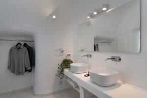 een witte badkamer met 2 wastafels en een spiegel bij White Concept Caves in Fira