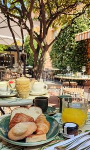 a table with plates of bread and a glass of orange juice at Hôtel La Pérouse Nice Baie des Anges in Nice