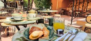a table with a plate of bread and a glass of orange juice at Hôtel La Pérouse Nice Baie des Anges in Nice