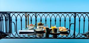 a table with food on a balcony overlooking the water at Hôtel La Pérouse Nice Baie des Anges in Nice