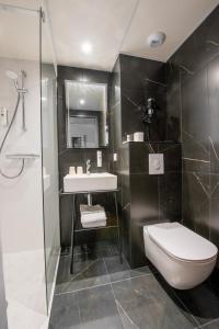y baño con aseo, lavabo y ducha. en Cit'Hotel Stim'Otel en Agen