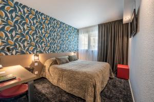 una camera d'albergo con letto, scrivania e finestra di Cit'Hotel Stim'Otel a Agen