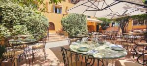 an outdoor patio with tables and chairs and an umbrella at Hôtel La Pérouse Nice Baie des Anges in Nice