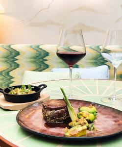 a table with a plate of food and a glass of wine at Hôtel La Pérouse Nice Baie des Anges in Nice