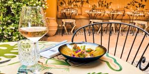 a bowl of food on a table next to a glass of wine at Hôtel La Pérouse Nice Baie des Anges in Nice
