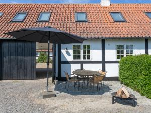 a table and chairs under an umbrella in front of a house at Sjælegård Countryside Lodge in Allinge