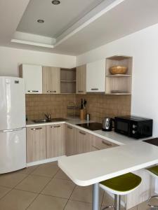 a kitchen with wooden cabinets and a white refrigerator at Family Lux Apartments - Lemon Garden and Pool in Becici