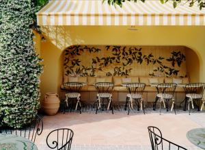a patio with chairs and a table and a wall at Hôtel La Pérouse Nice Baie des Anges in Nice