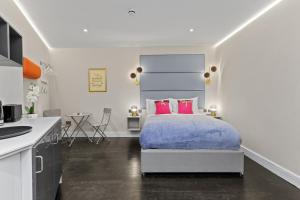a bedroom with a king sized bed with pink pillows at Modern Studio Flat in London
