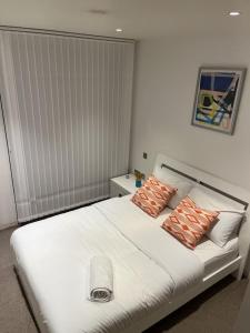 una camera da letto con un grande letto bianco con cuscini di Beautiful 2 bed Flat in Finchley Road, Camden a Londra
