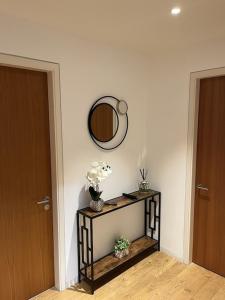 Zimmer mit einem Spiegel und einem Tisch mit Blumen in der Unterkunft Beautiful 2 bed Flat in Finchley Road, Camden in London