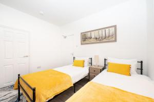 2 camas en una habitación con paredes blancas y sábanas amarillas en Brinton's Road - Modern Studio Apartments in City Centre en Southampton