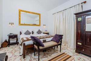 安君纳The Tamarind Hotel - A Boutique Heritage Stay, Anjuna - Goa的卧室里有一张床，墙上有一面镜子