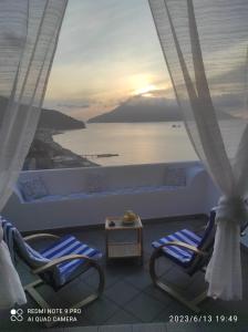 Un balcón con sillas y vistas al océano. en Appartamento Rocche Rosse en Acquacalda