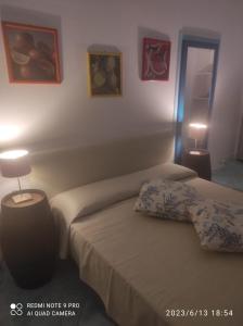 a bedroom with two beds and a lamp on the wall at Appartamento Rocche Rosse in Acquacalda
