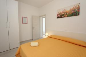 een slaapkamer met een oranje bed en een schilderij aan de muur bij Ville Pinetine in Bibione