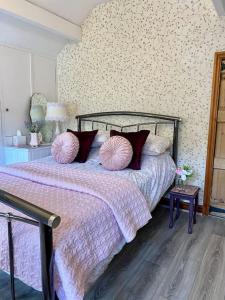 a bedroom with a bed with two pink pillows at Beautiful Village Cottage 5 mins to Alton Towers in Alton
