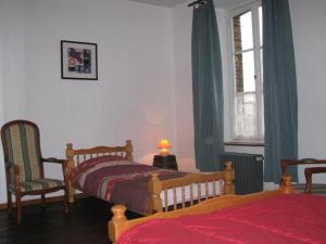 a bedroom with two beds and a chair and a window at L'escaille in Brognon