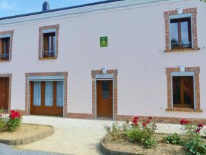 - un bâtiment blanc avec des portes en bois et des fleurs dans l'établissement Gite de vieille maison rouge, à Rocroi